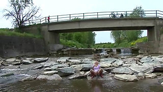 Blonde pissing outside in a river